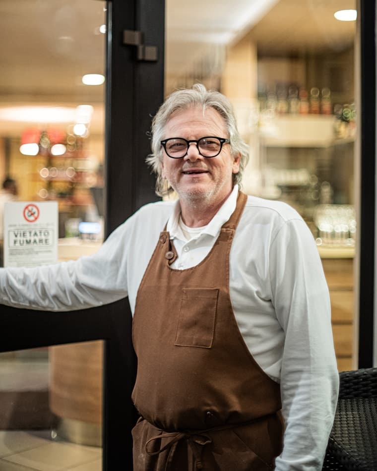 Le patron, en tablier, sur le pas de son établissement